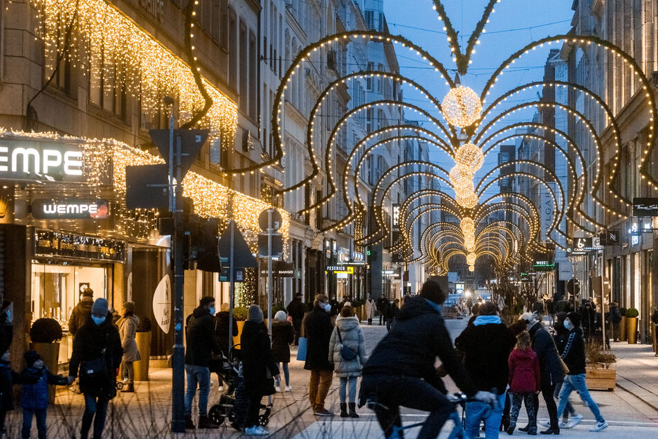 Menschen flanieren durch die weihnachtlich illuminierte Innenstadt.