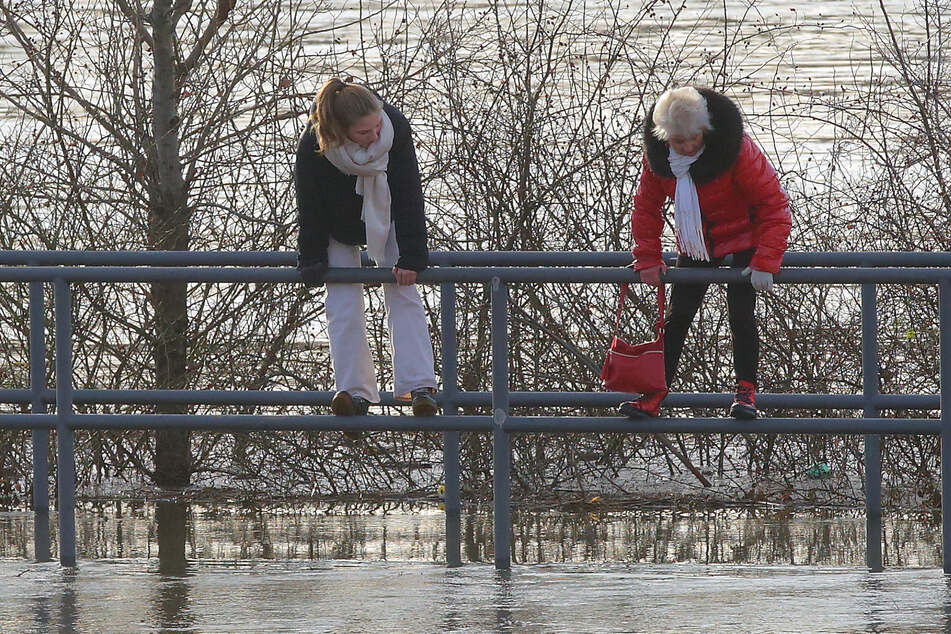 Da von der Molenbrücke nur noch die Geländer herausragen, nutzen diese beiden Damen sie, um trockenen Fußes voranzukommen.