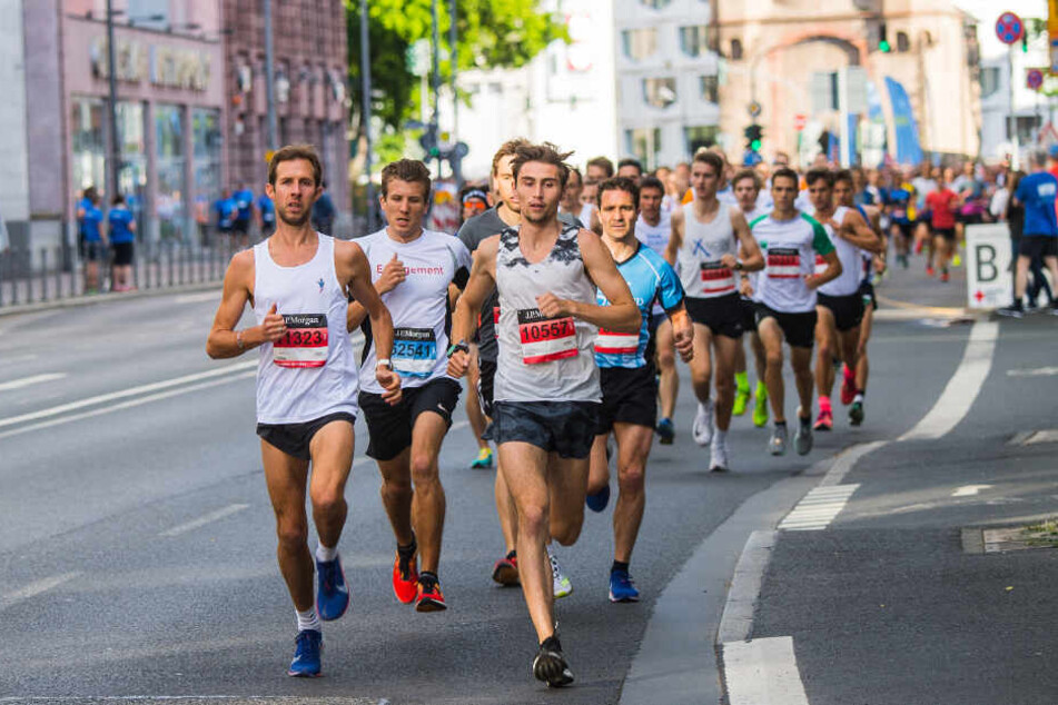 Die Spitzengruppe läuft kurz nach dem Start über die Eschersheimer Landstraße mit dem Eschenheimer Tor im Hintergrund. In der Innenstadt der Mainmetropole findet der Firmenlauf J.P. Morgan Corporate Challenge statt.