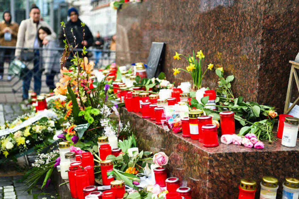Menschen stehen um das Brüder Grimm Denkmal, an dem Blumen und Kerzen niedergelegt worden sind.