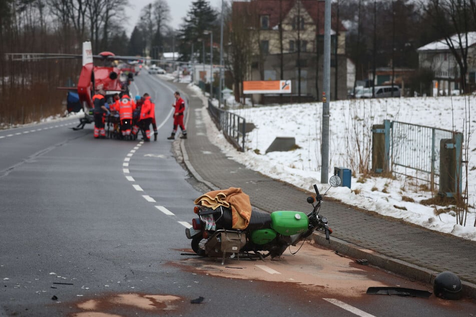 Rettungskräfte bringen einen schwerverletzten Mopedfahrer in ein Krankenhaus. Im Vordergrund: Das Moped des Verunfallten.