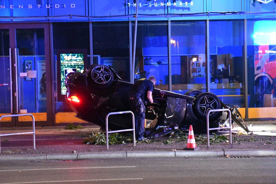 Der Mercedes kam auf dem Dach abseits der Fahrbahn zum Stehen. Äste, Blätter und ein verbogenes Fahrrad vor dem Wagen zeugen von dem Trümmerfeld, das der Unfall hinterließ.