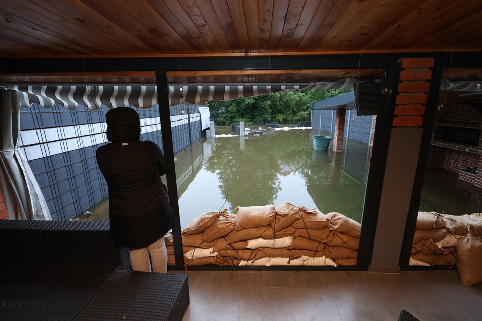 Eine Frau steht in ihrem Wintergarten in Burgau vor ihrem vom Hochwasser der Mindel überfluteten Garten.