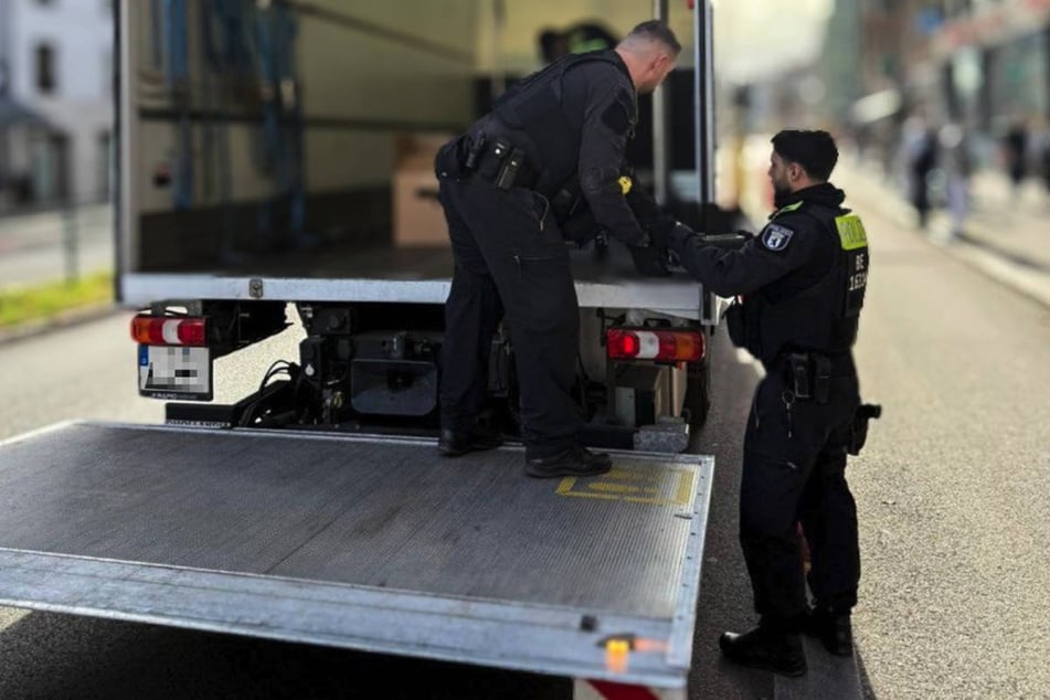Polizeibeamte verstauen das sichergestellte Beweismaterial in einem Lkw.