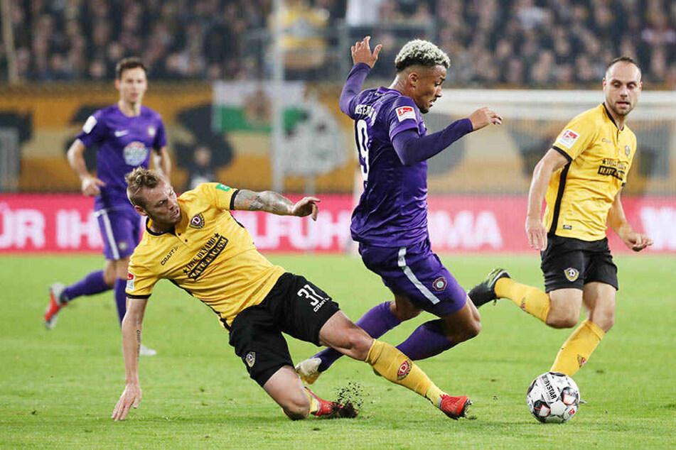 Aues Emmanuel Iyoha (M) behauptet sich im Zweikampf gegen Dynamos Brian Hamalainen (l.).