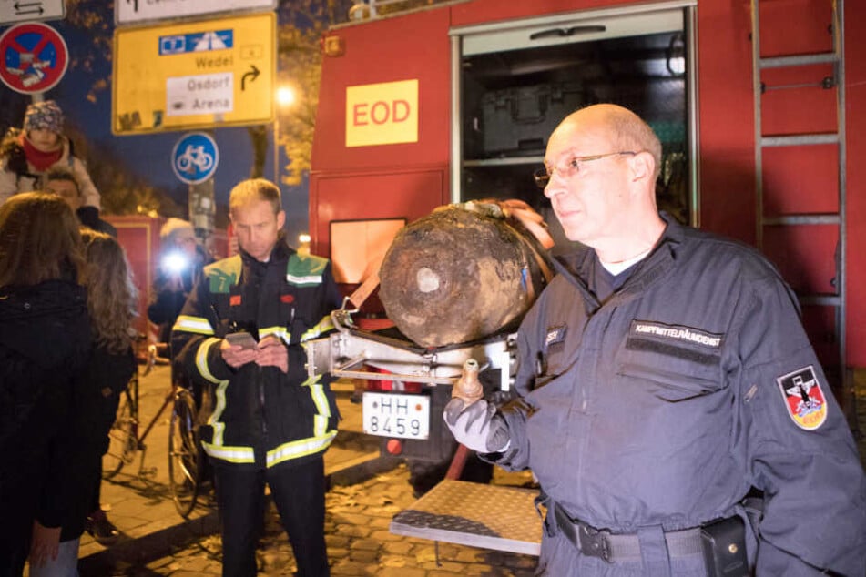 Der Sprengmeister zeigt sich nach der Entschärfung mit dem Zünder in der Hand und der Bombe im Hintergrund.