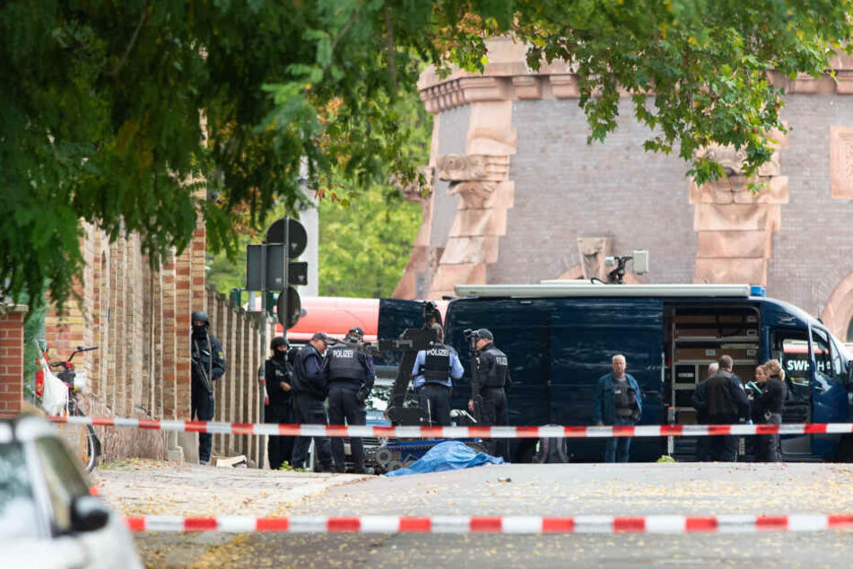 Halle am 9. Oktober: Polizisten sichern an der Mauer zur Synagoge die Umgebung, auf der Straße liegt abgedeckt eines der Opfer.