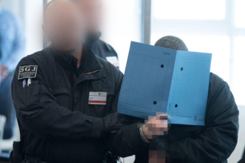 Ein Angeklagter im Prozess gegen die selbsternannte "Revolution Chemnitz" wird im Prozessgebäude des Oberlandesgerichts Dresden zu Prozessbeginn in den Verhandlungssaal geführt. Die insgesamt acht Männer zwischen 21 und 32 Jahren sind wegen Bildung einer