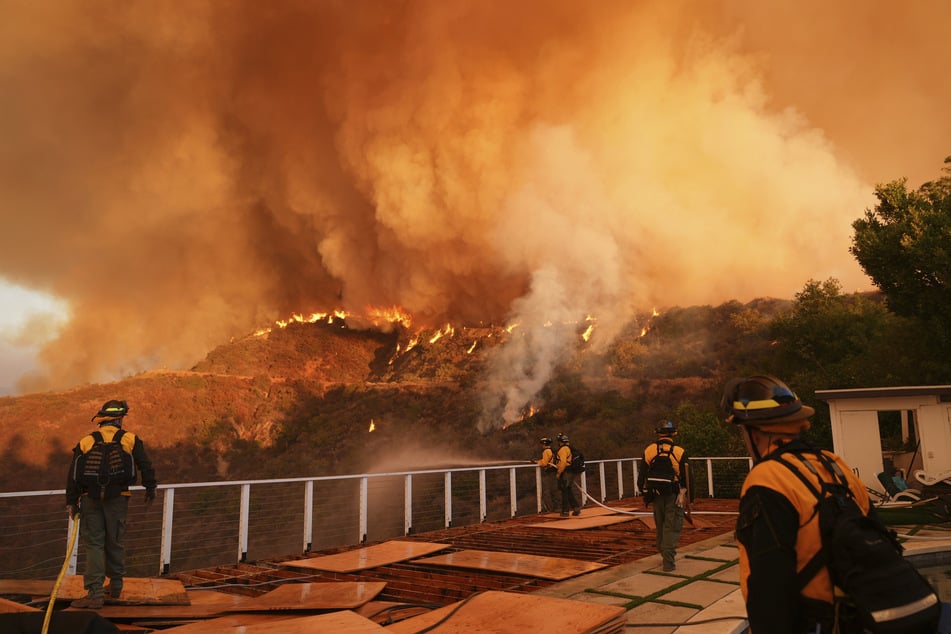 Feuerwehrleute überwachen das Palisades-Feuer im Mandeville Canyon.