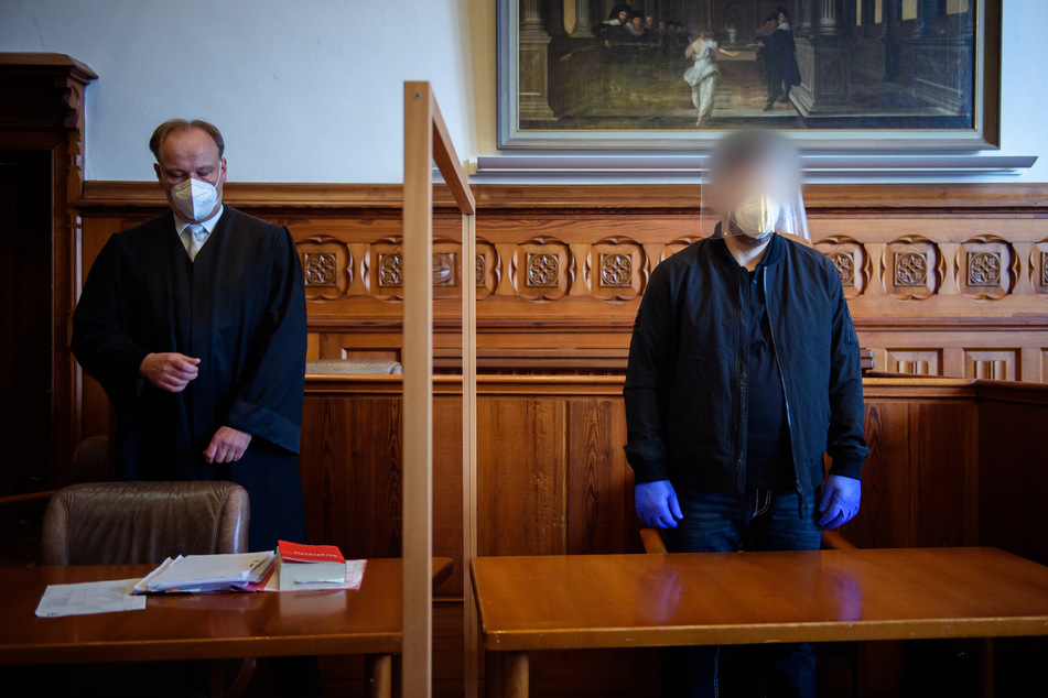 Der Angeklagte (r.) steht im Gerichtssaal neben seinem Anwalt. Dem 47-jährigen Mann wird die Vergewaltigung und Ermordung seiner Ehefrau vorgeworfen.