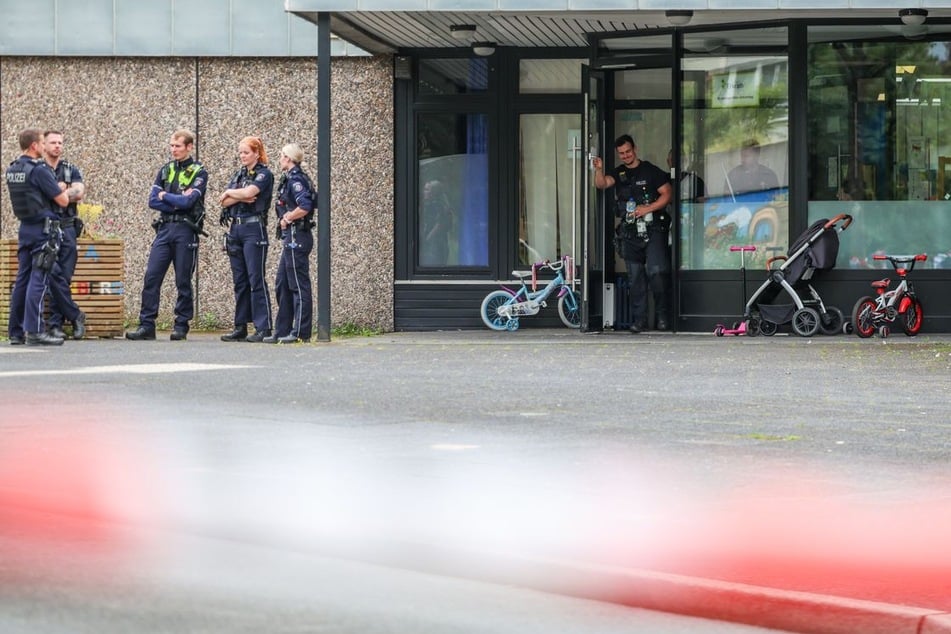 Polizisten stehen an der Kindertagesstätte, vor der es am Dienstag zu einer Schussabgabe gekommen war.