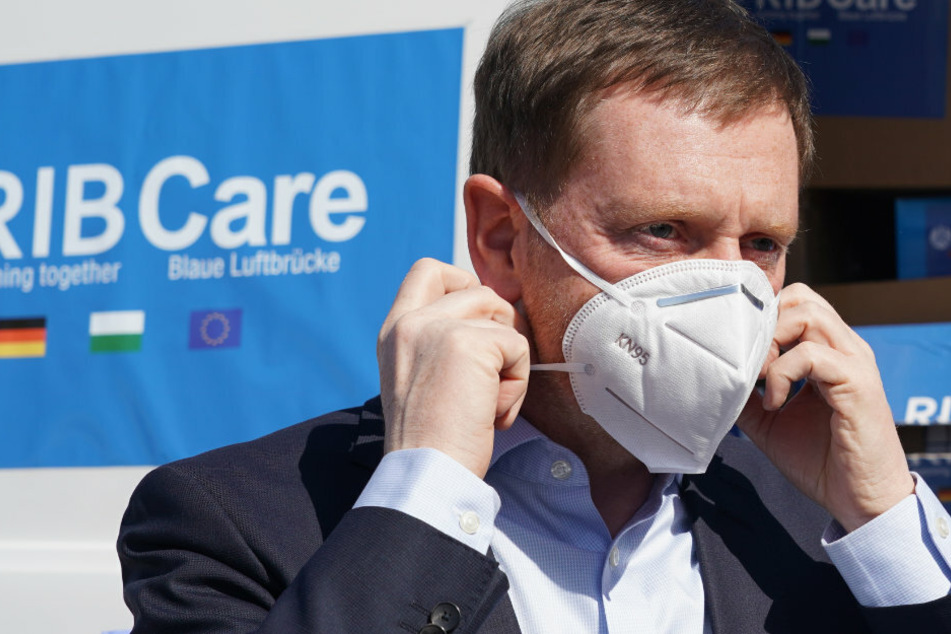 Prime Minister Michael Kretschmer puts on a face mask.