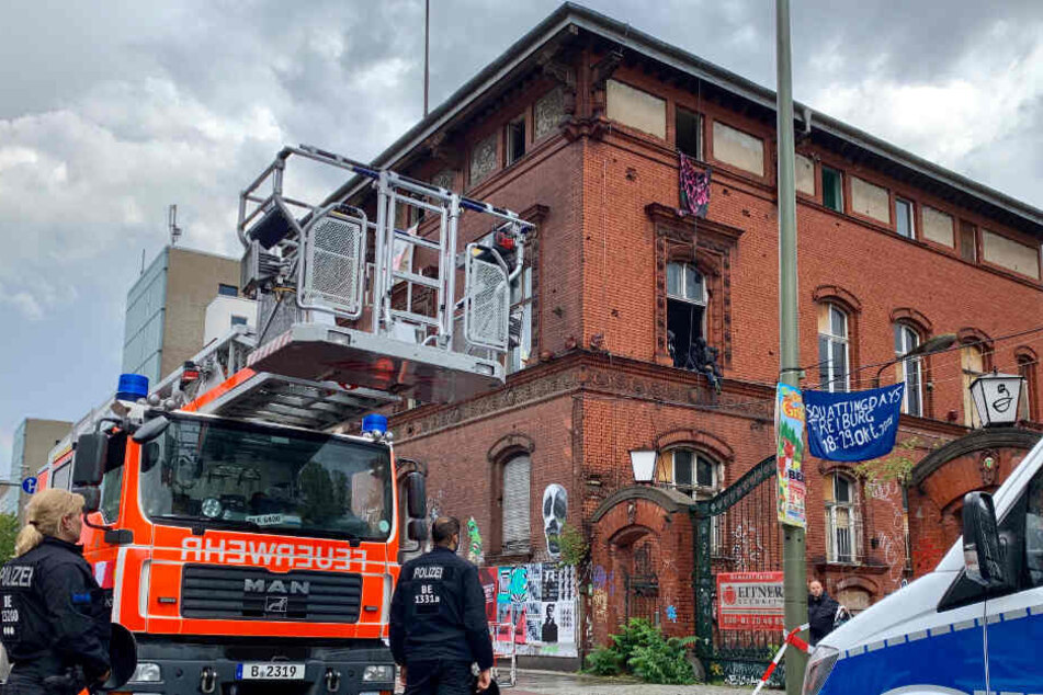 Einsatzkräfte von Polizei und Feuerwehr stehen im Bezirk Friedrichshain vor einem leerstehenden Industriegebäude, in das Unbekannte mit Kletterausrüstung eingedrungen waren und es besetzt haben.