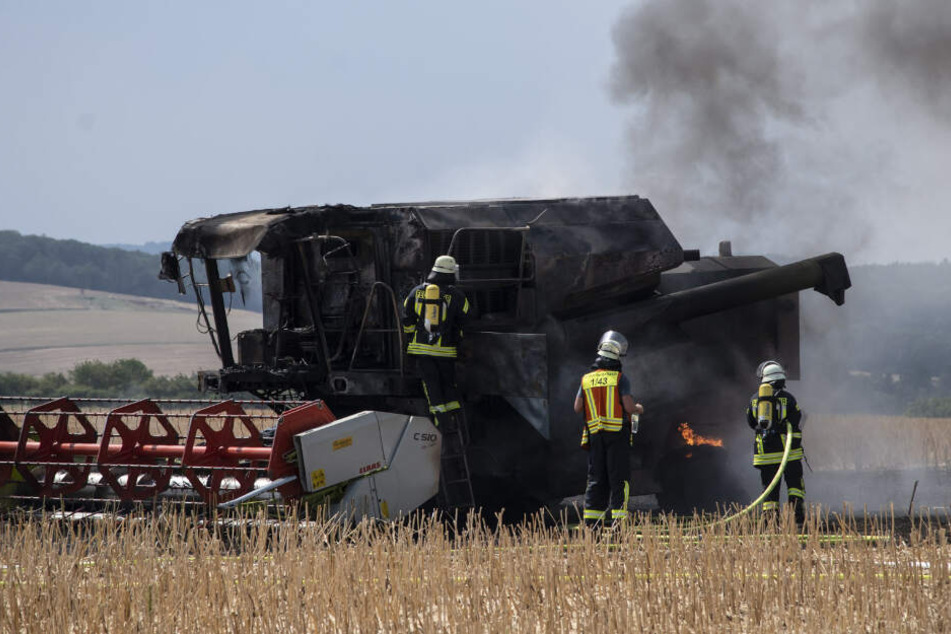 Feuerwehrleute löschen die letzten Flammen am Mähdrescher.