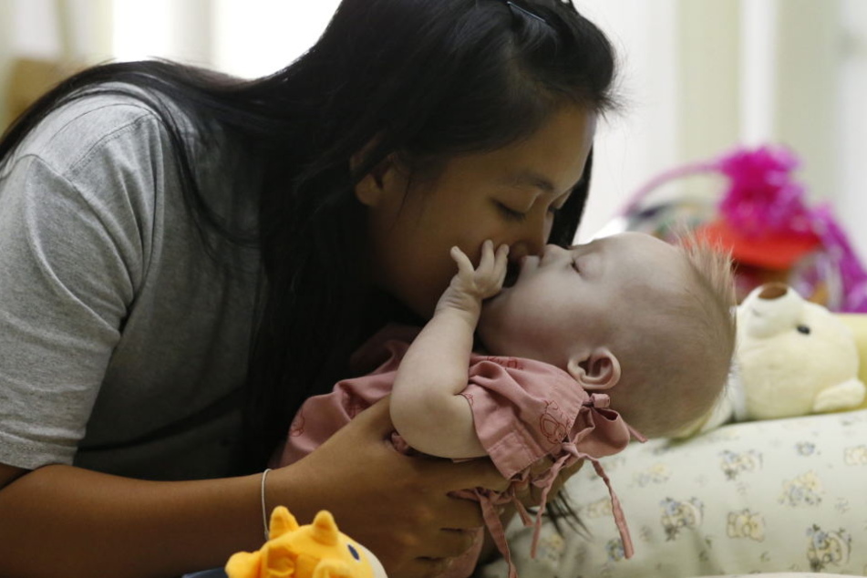 Eine Mutter küsst ihr Baby mit Down-Syndrom (Symbolbild)
