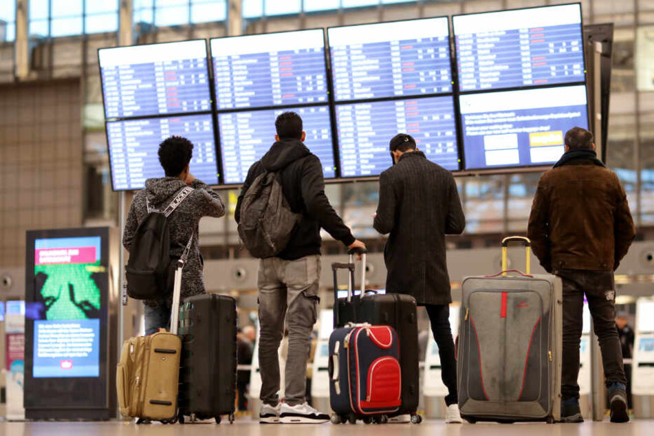Reisende stehen am Flughafen Hamburg und informieren sich über die Abflüge und Ankünfte. Donnerstag dürften viele Flüge ausfallen.