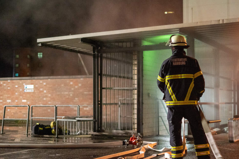 Ein Feuerwehrmann steht vor einem Aufgang der verqualmten Tiefgarage.