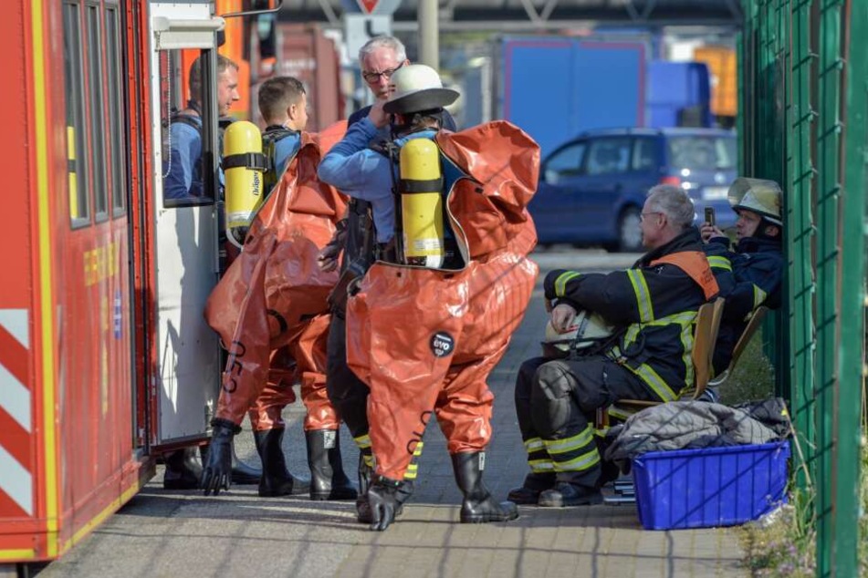 Feuerwehrmänner legen spezielle und vor allem gegen Chemikalien extrem resistente Schutzanzüge an, um den Brand nach dem Chemieunfall zu bekämpfen.