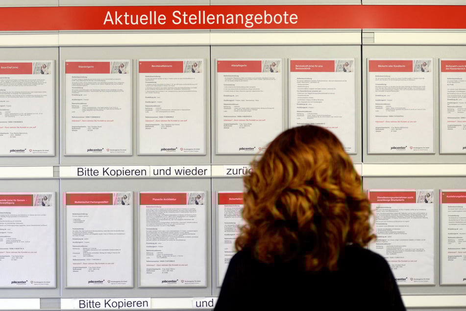 Eine Frau schaut sich die Jobangebote in der Arbeitsagentur an. Gegenwärtig zeigen die Unternehmen eine verhaltene Einstellungsbereitschaft.
