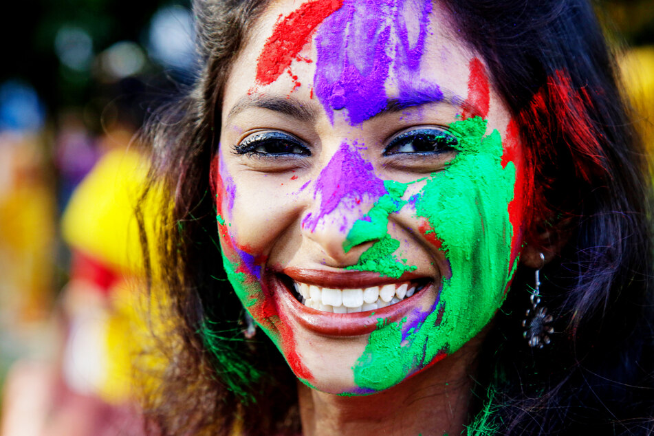 Eine mit Farbe bemalte Frau lächelt während des Holi-Festes in Kalkutta, Indien.