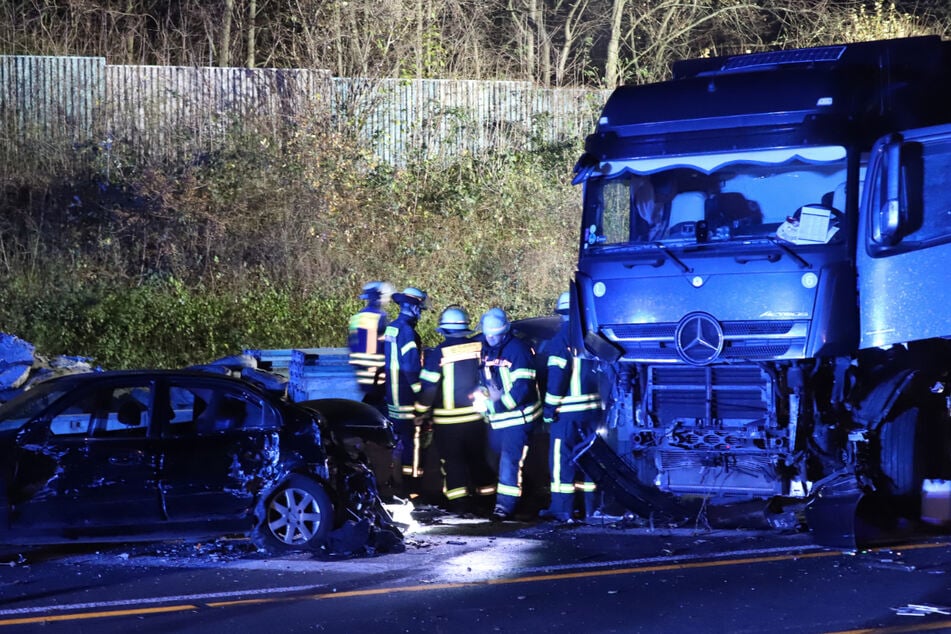 Einsatzkräfte der Feuerwehr stehen neben dem polnischen Lastwagen auf der A1 bei Hagen an der Unfallstelle.