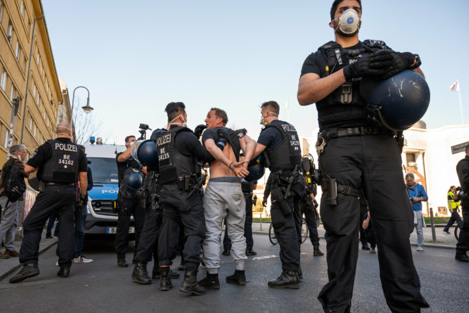 Polizisten mit Atemschutzmasken nehmen einen Demonstranten auf dem Rosa-Luxemburg-Platz fest.