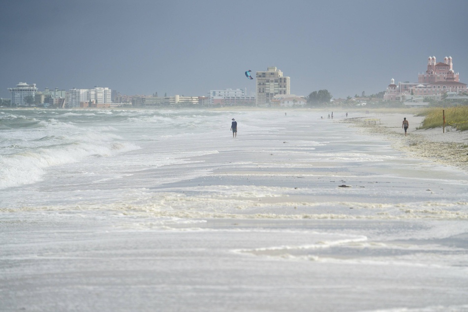 Floridians walk along the sand the morning after Tropical Storm Elsa moved over the Tampa Bay Area and up the west coast of Florida.