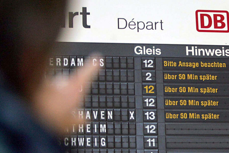 Ein Reisender betrachtet im Hauptbahnhof von Osnabrück eine Anzeigentafel, die die Verspätungen im Zugverkehr anzeigt.