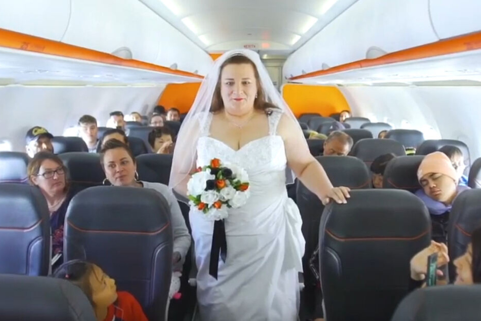 In einem weißen Kleid schritt Cathy Rolfe die Reihen des Flugzeugs entlang.
