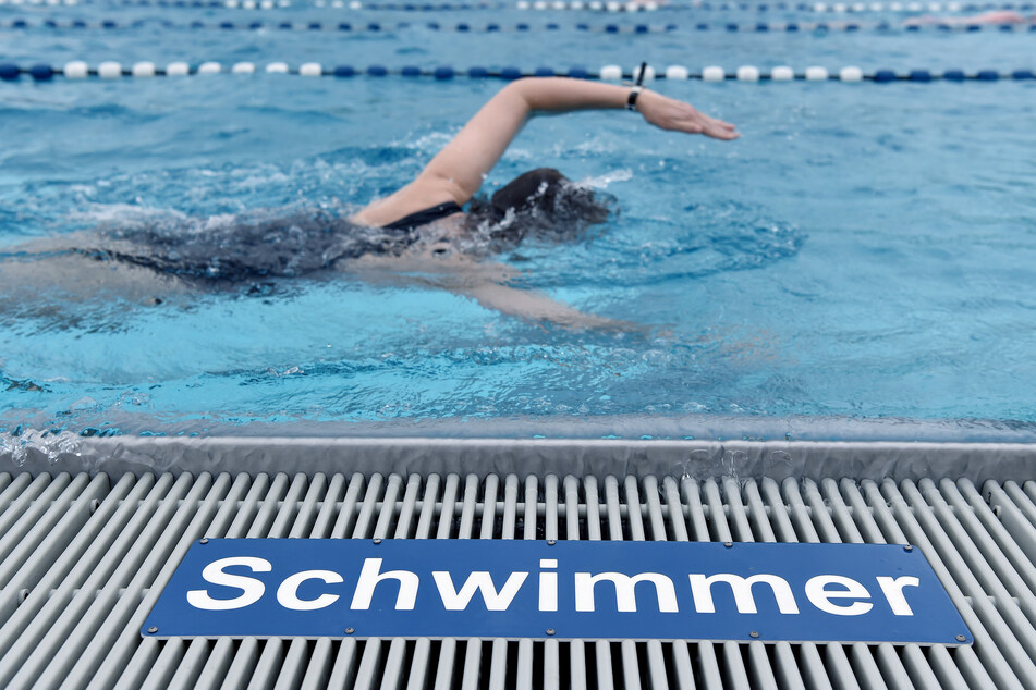 Eine Frau schwimmt Bahnen in einem Freibad.