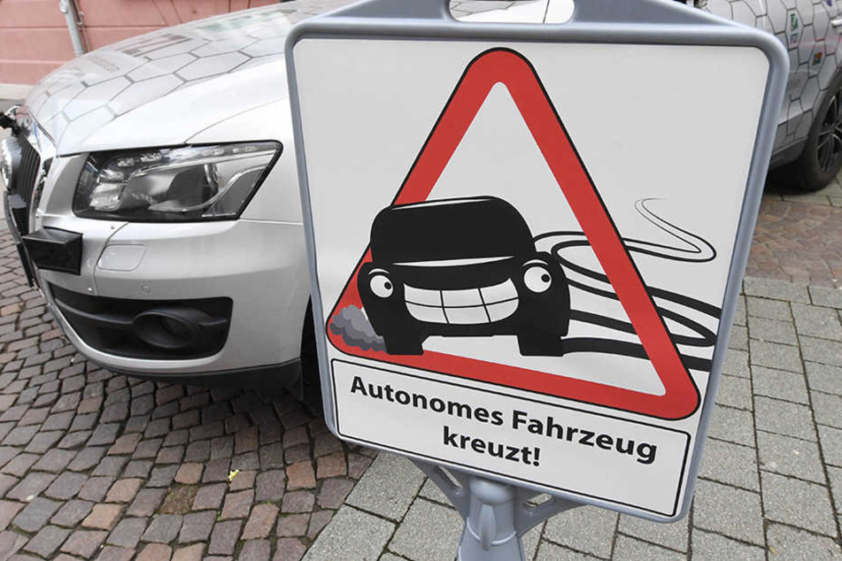 "Autonomes Fahrzeug kreuzt!" - Ein Schild macht auf das Forschungsfahrzeug "Cocar" für autonomes Fahren aufmerksam.