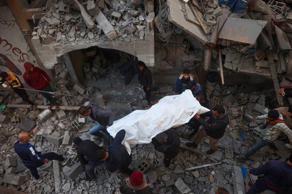 People pull out bodies of casualties from the rubble of a building destroyed in an Israeli strike on the Bureij camp for Palestinian refugees in the central Gaza Strip on January 8, 2025.