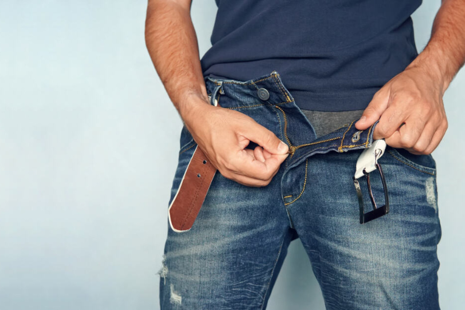 Ein Mann knöpft sich seine Jeans auf. (Symbolbild)