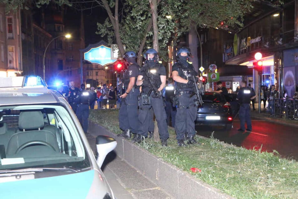 Polizisten stehen auf dem begrünten Mittelstreifen der Karl-Marx-Straße.