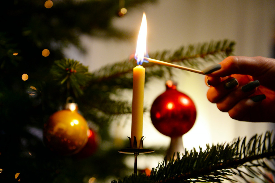 Eine Frau zündet an einem Weihnachtsbaum eine Kerze an. (Symbolbild)