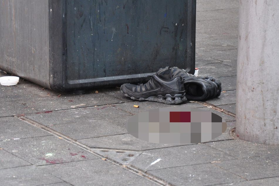Ein Paar Schuhe steht neben einer Blutlache am Tatort.