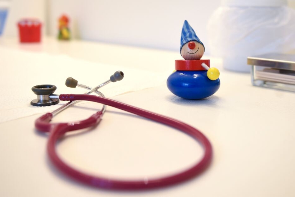 Ein Stethoskop und Kinderspielzeug liegen in einer Kinderarztpraxis auf einem Tisch.