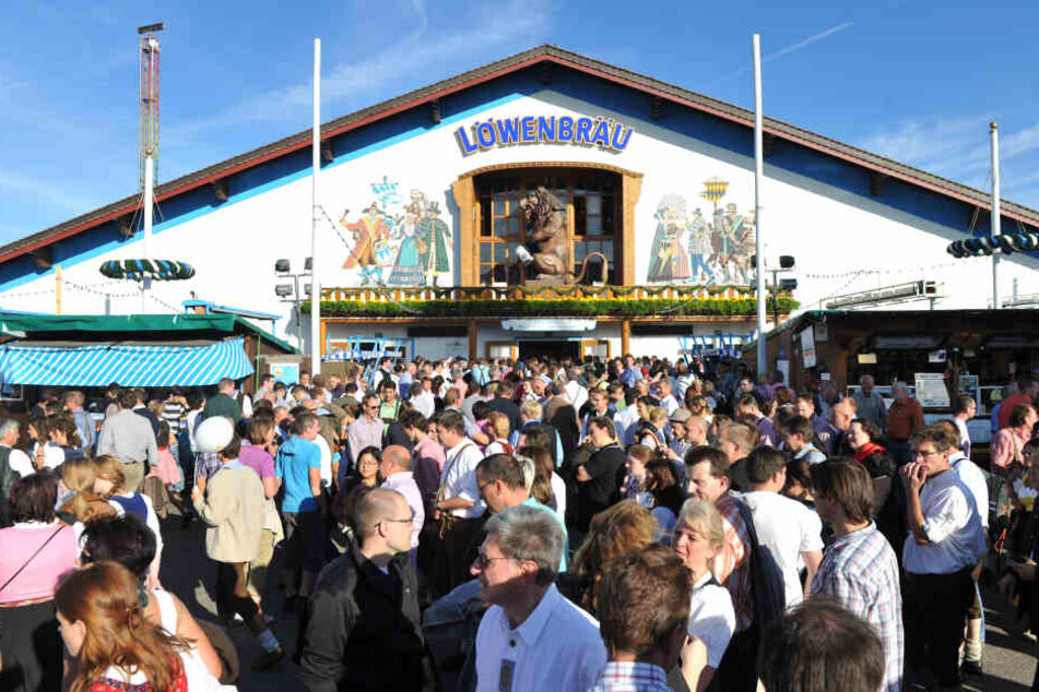 Oktoberfestbesucher stehen vor der Löwenbräu-Festhalle auf der Wiesn.