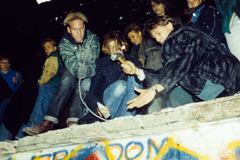 West-Berliner versuchen mit Hämmern und Kreuzhacken die Berliner Mauer einzureißen.