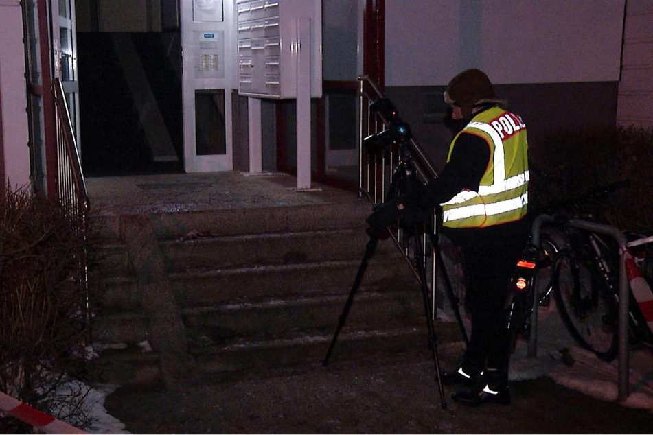 Ein Kriminaltechniker der Polizei macht Aufnahmen von den Blutspuren im Eingangsbereich des Mietshauses in Berlin-Lichtenberg.