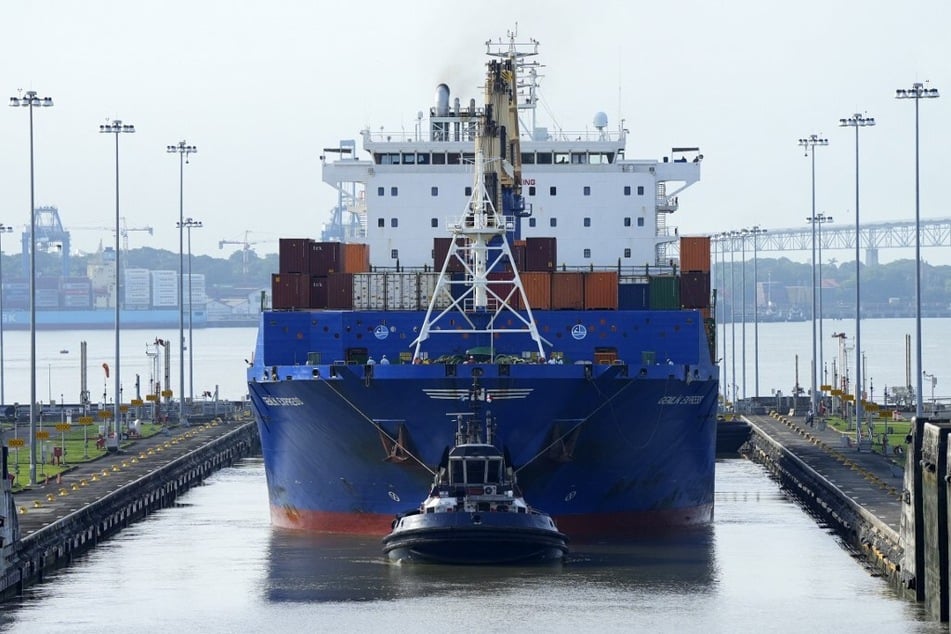 A cargo ship and tugboat sail through the Cocoli Locks at the Panama Canal.