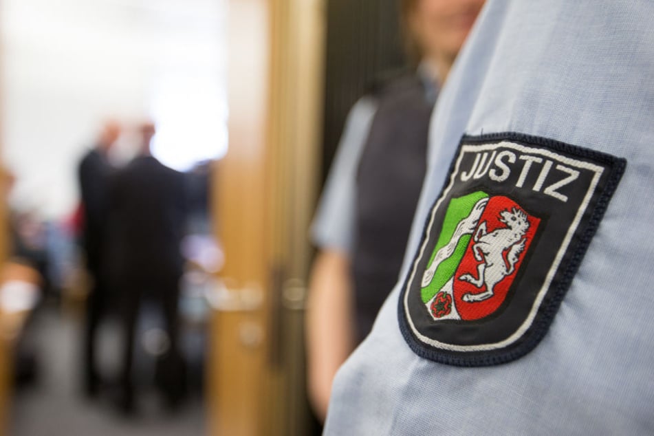 Ein Justizbeamter steht beim Prozessauftakt nach dem Tod eines Streitschlichters vor dem Sitzungssaal. Zwei Angeklagte müssen sich wegen fahrlässiger Tötung verantworten.