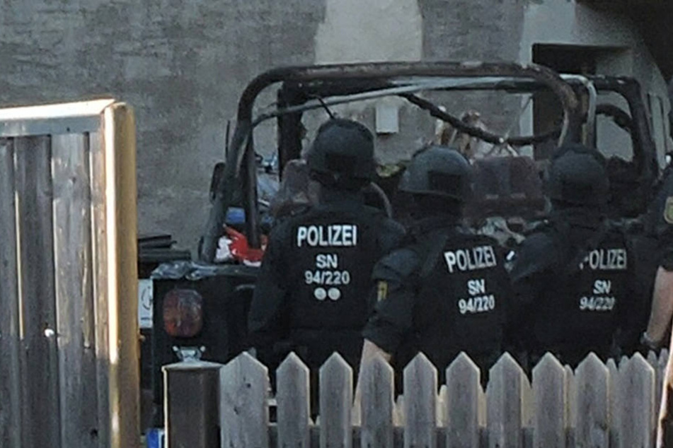 Der ausgebrannte Jeep, der vor dem Wohnhaus parkt, steht in keiner Verbindung zu der Hausdurchsuchung.