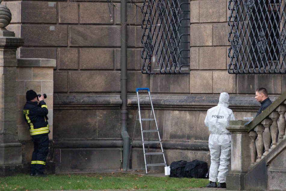 Einsatzkräfte der Polizei stehen im Bärengarten neben dem durchtrennten Gitterfenster des Grünen Gewölbes am Residenzschloss.