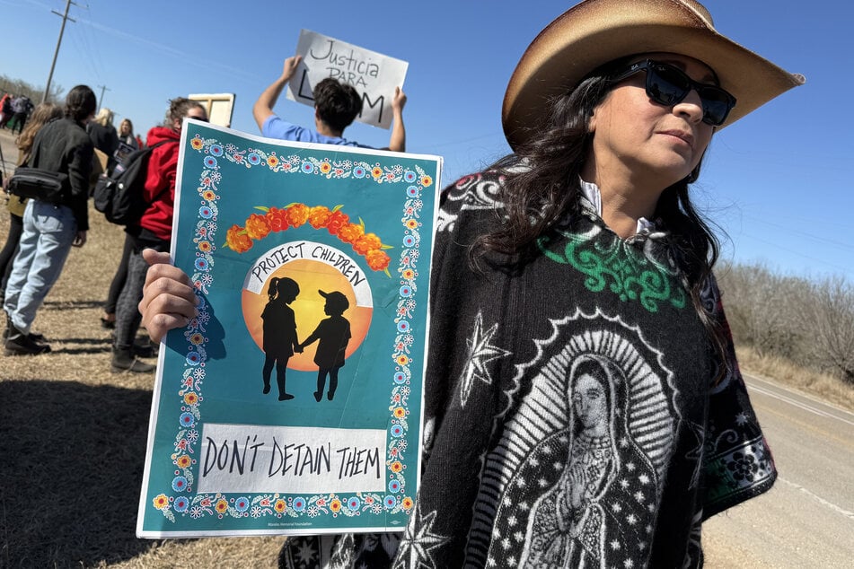 A person holds a sign calling to protect, not detain, children as people gather during a demonstration and vigil outside the South Texas Family Residential Center in Dilley, Texas, on January 28, 2026.
