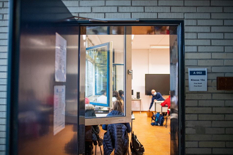 Schüler und Schülerinnen sitzen zum Schulbeginn in Nordrhein-Westfalen nach den Herbstferien bei geöffneten Fenstern und Türen in einer Klasse der Freiherr-vom-Stein-Realschule in Gütersloh.