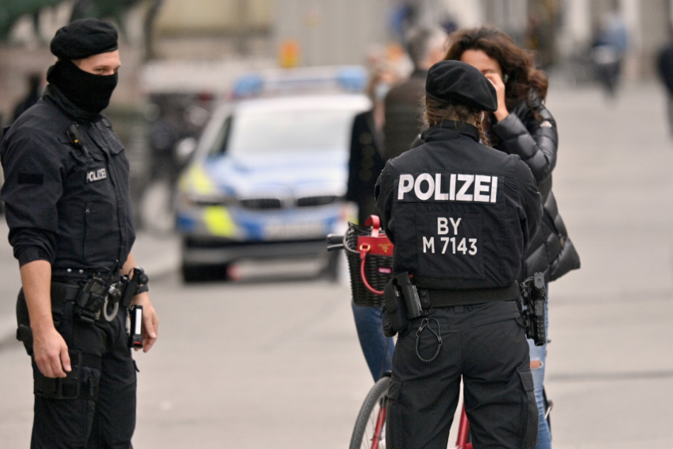 Polizisten kontrollieren in der Innenstadt die Einhaltung der Maskenpflicht bei einer Radfahrerin. (Symbolbild)