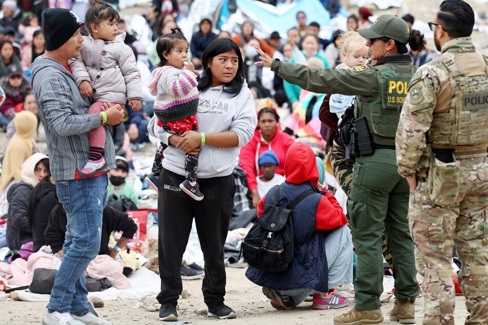 A US Border Patrol agent speaks to immigrants before they are transported from a makeshift camp.