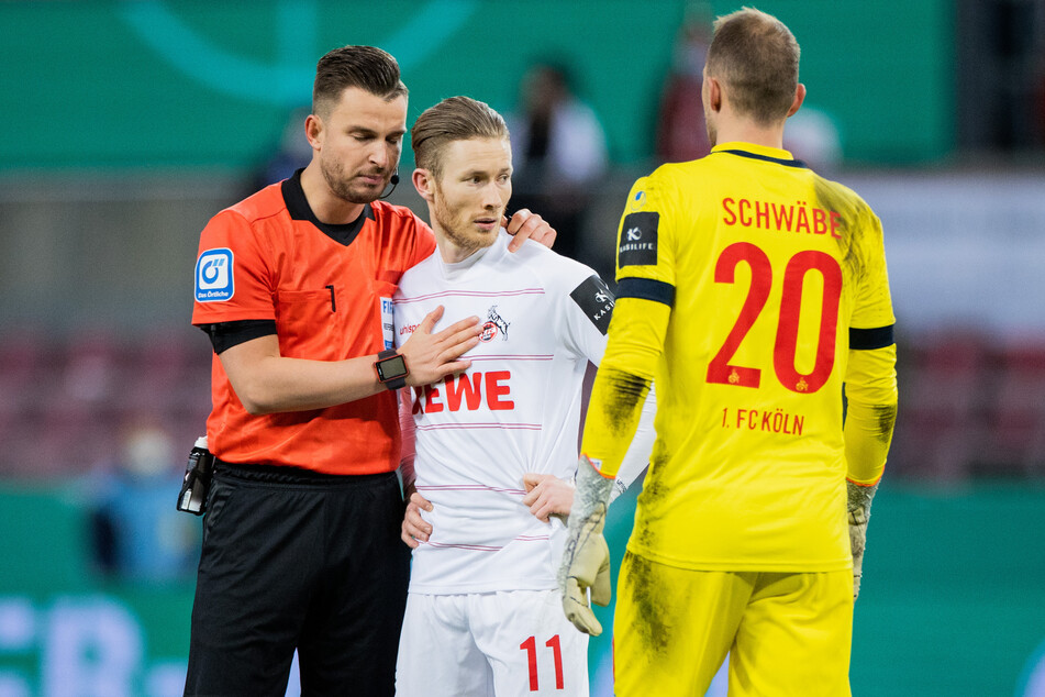 Referee Daniel Schlager (left) comforts Florian Kainz (29) after he touched the ball twice during a penalty.