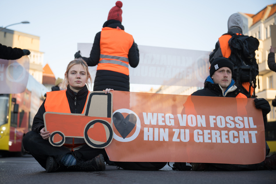 Diese Bilder sollen der Vergangenheit angehören: Aktivisten der Klimaschutzgruppe Letzte Generation sitzen bei einer Straßenblockade auf dem Innsbrucker Platz mit einem gemalten Traktor und einem Banner "Weg von fossil hin zu gerecht" auf der Straße.